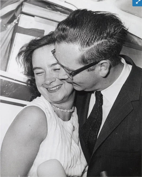 A photo of Russel Mock giving his wife, Jerrie Mock, a kiss on the cheek by her Cessna 180.