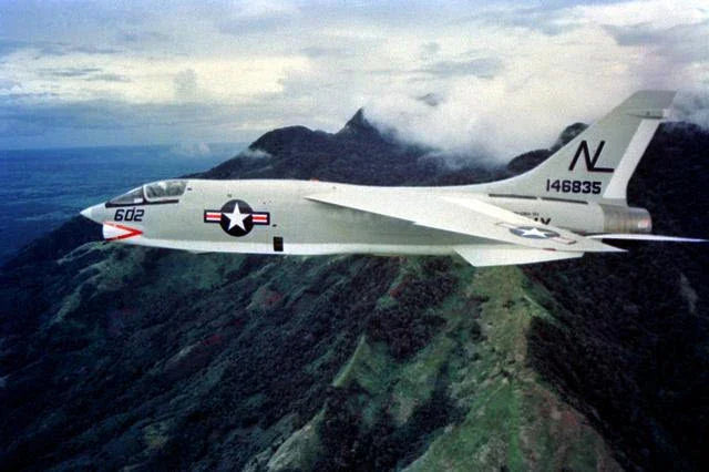 A photo of an RF-8 Crusader fighter jet flying over the mountains of Vietnam.