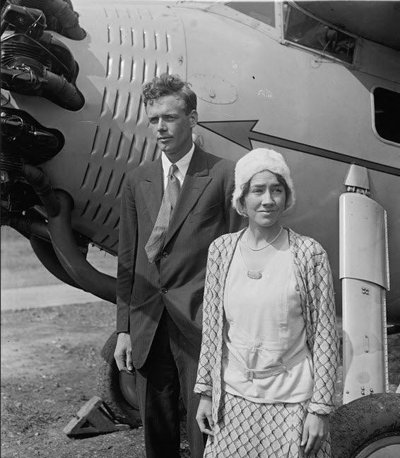 A photograph of Charles Lindbergh and his wife standing in front of an airplane.