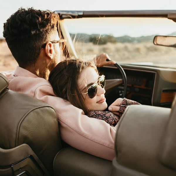 A photo of a couple relaxing on a drive in bright sunlight wearing AO Original Pilot sunglasses.