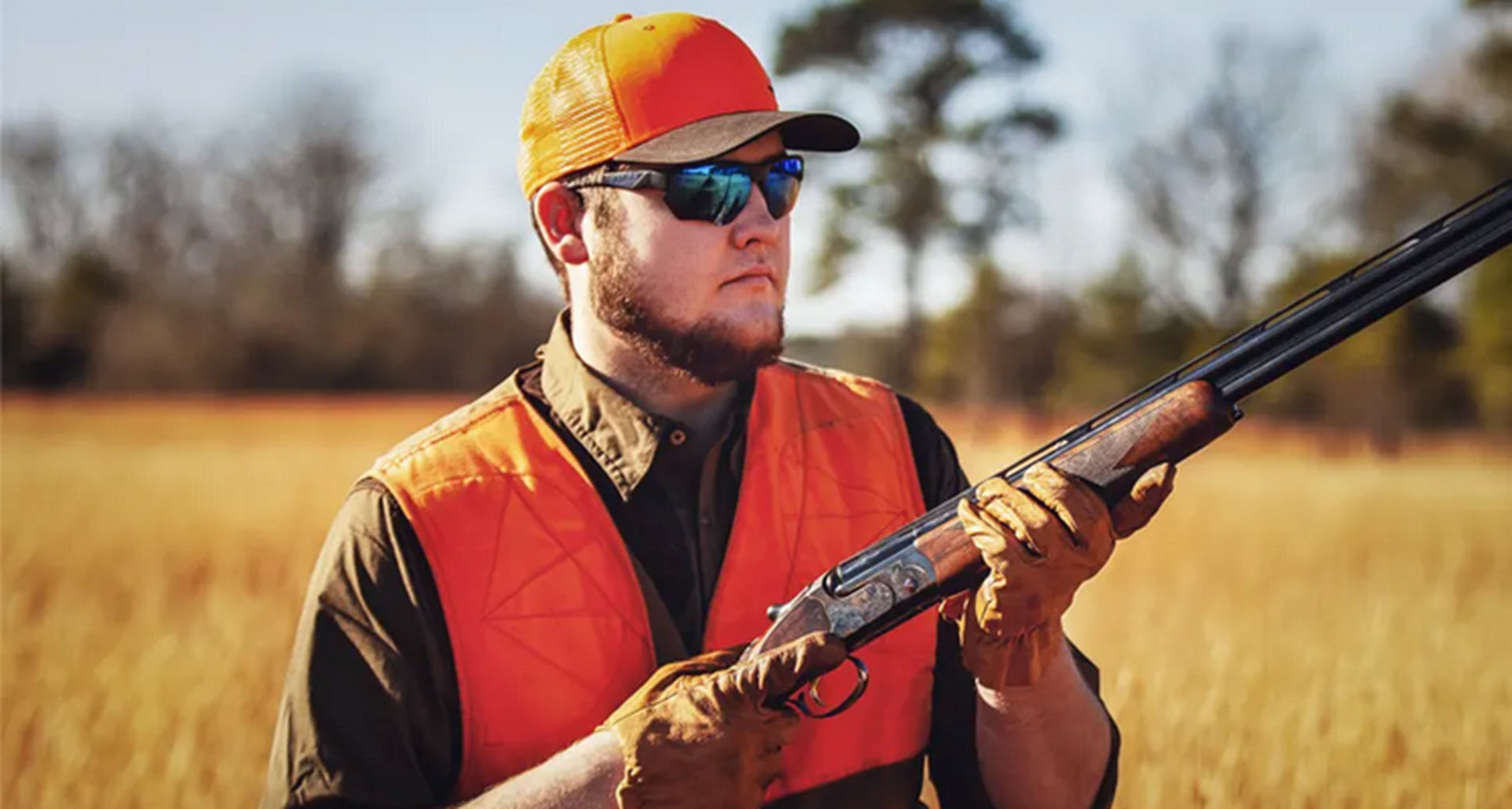 A photograph of an outdoor sportsman hunting with his shotgun and wearing a pair of RE Ranger Phoenix sunglasses.