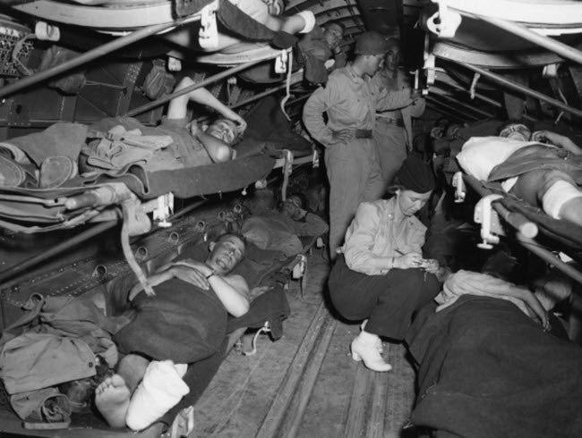 A photo of a Flight Nurse, Lt. Katye Swope, 802d Medical Air Evacuation Transport Squadron, U.S. Army Air Forces, checks the name of a patient aboard a transport enroute from Sicily to North Africa, 25 July 1943.