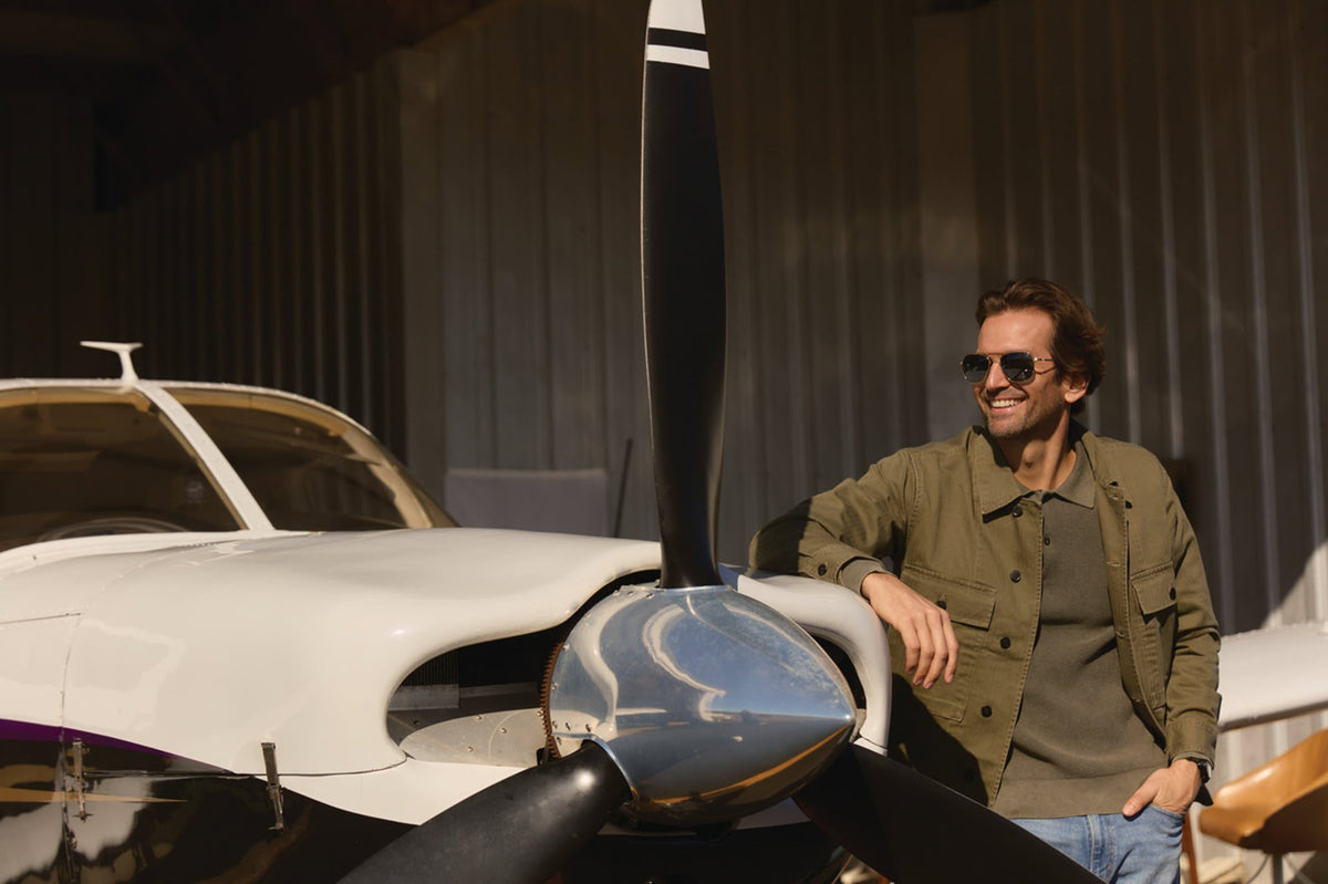 A pilot leaning on his aircraft wearing a pair of AO Original Pilot sunglasses.