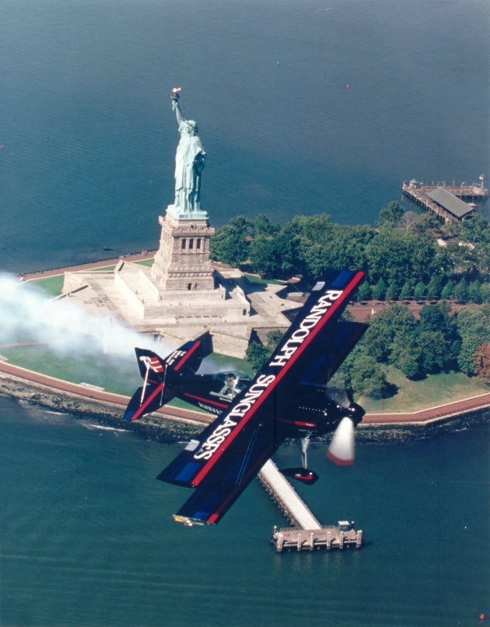 Sean D. Tucker, aerobatic pilot sponsored by Randolph Engineering, Inc., airborne passing the Statue of Liberty in New York City