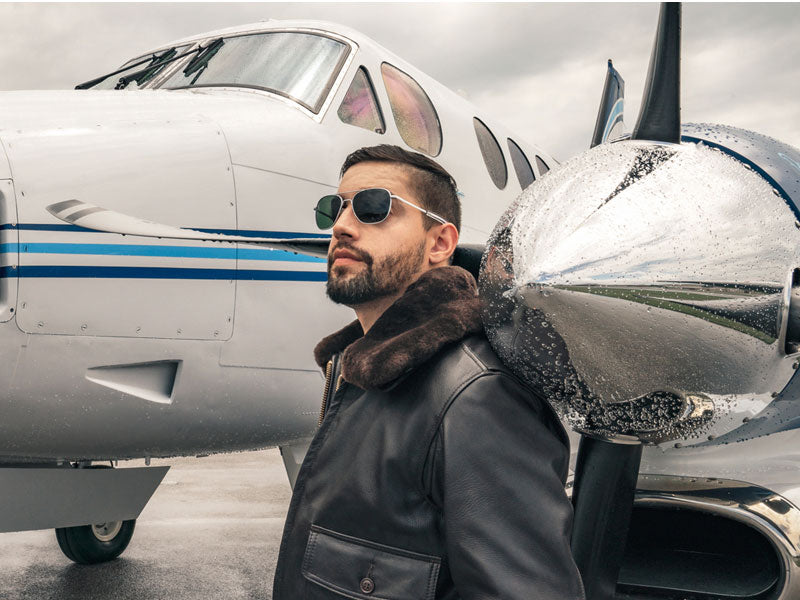 A pilot standing in front of a Beech King Air wearing Randolph Matte Chrome Aviator sunglasses with American Gray Lenses for excellent visual acuity.