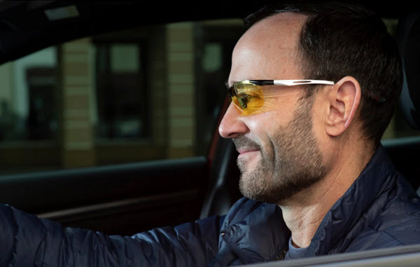 A photograph of a man wearing Eagle Eyes Fusion Night sunglasses driving at night.