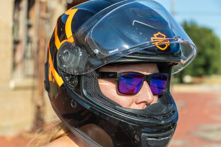 A photograph of a motorcyclist with a helmet on wearing a pair of Kingfisher Mirrored Sapphire cycling sunglasses.