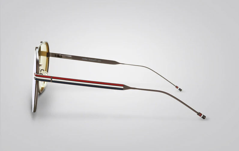 A pair of aviator style frame sunglasses shown in side profile on a light gray background. The frames are black, and the temples feature a signature red, white, and blue stripe detail.