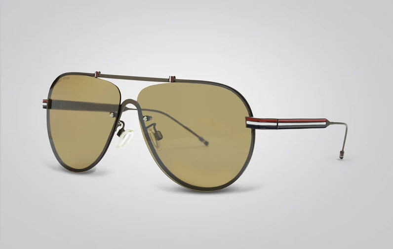 A pair of aviator sunglasses with a dark metal frame, yellow-tinted lenses, and signature red, white, and blue stripes on the temples, shown on a light gray background.