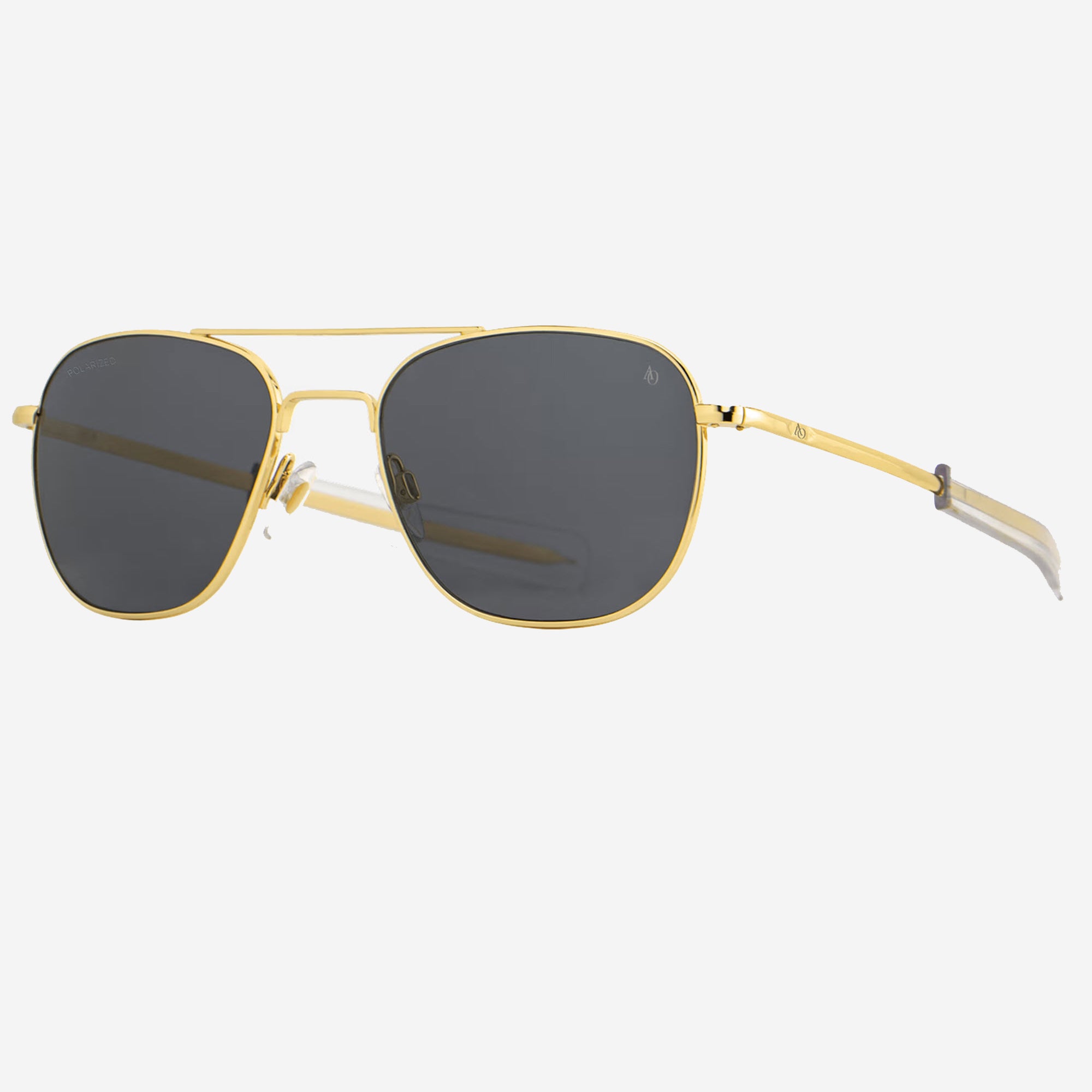 A pair of AO Original Pilot aviator-style sunglasses with a gold metal frame and dark gray lenses, shown from a side angle against a light gray background.
